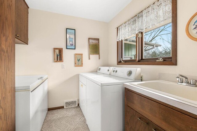 clothes washing area featuring separate washer and dryer, light colored carpet, sink, and cabinets