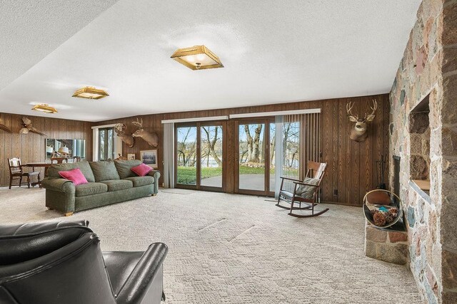 carpeted living room with a textured ceiling and wooden walls