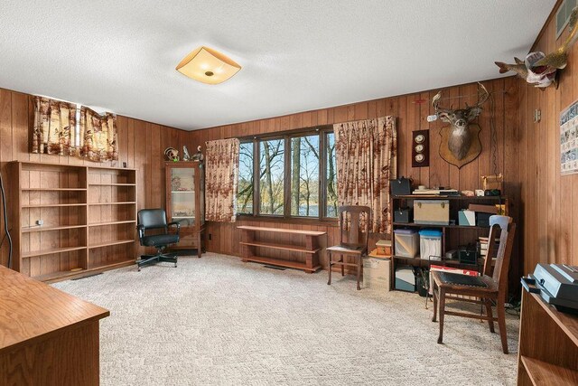 office with wood walls, carpet floors, and a textured ceiling