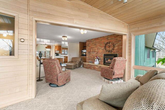 living room featuring wood walls, a fireplace, lofted ceiling, and carpet flooring