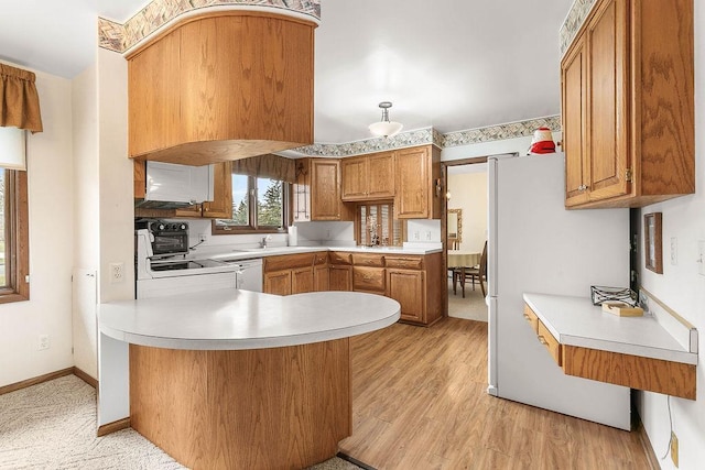 kitchen with electric stove, sink, white dishwasher, light hardwood / wood-style flooring, and kitchen peninsula