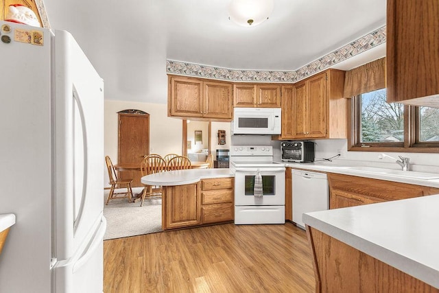 kitchen featuring sink, kitchen peninsula, light hardwood / wood-style flooring, and white appliances