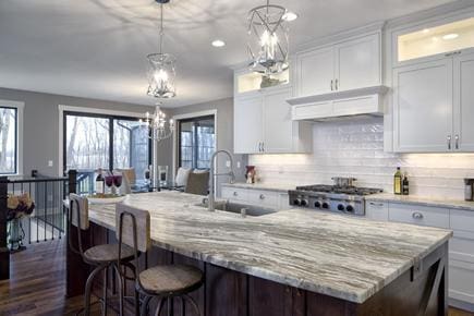 kitchen featuring white cabinets, pendant lighting, and a center island with sink