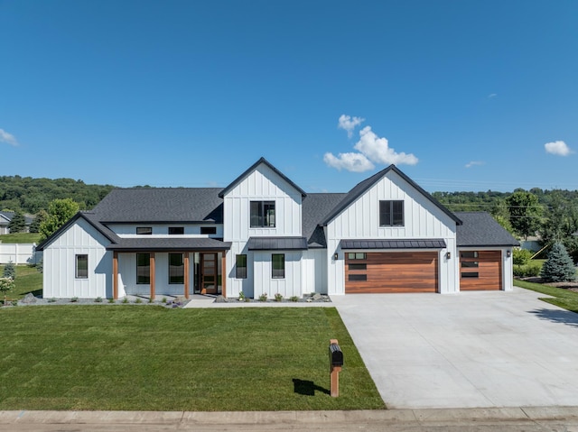 modern inspired farmhouse featuring covered porch, a garage, and a front lawn