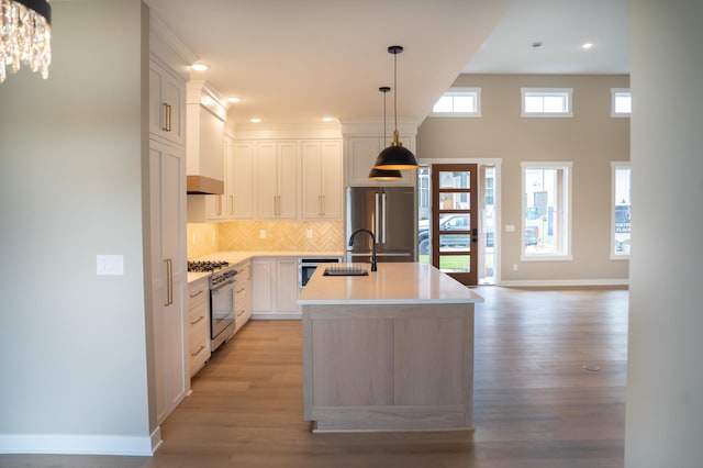 kitchen with appliances with stainless steel finishes, white cabinetry, tasteful backsplash, an island with sink, and sink