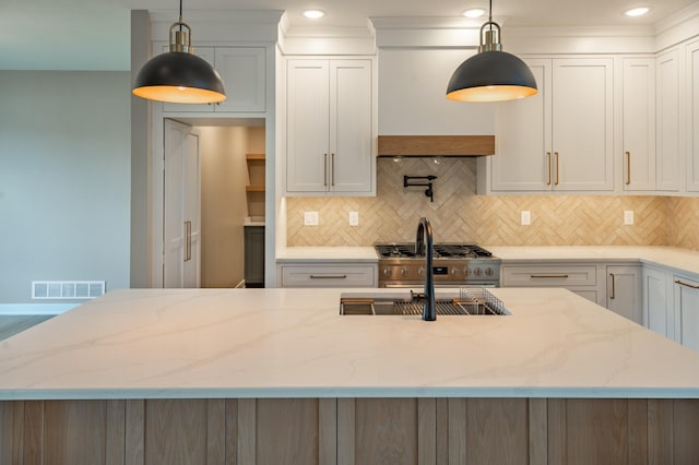 kitchen with decorative light fixtures, backsplash, white cabinetry, and light stone countertops