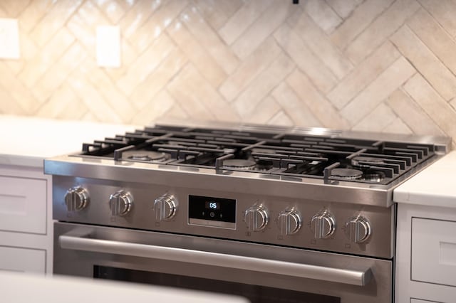 interior details featuring decorative backsplash and stainless steel range with gas stovetop