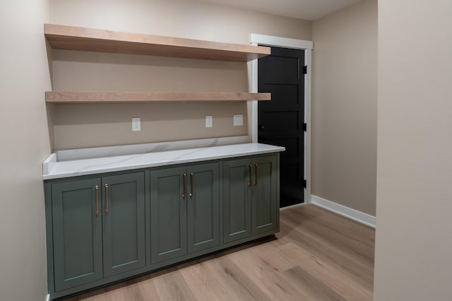 interior space featuring light wood-type flooring, light stone counters, and green cabinetry