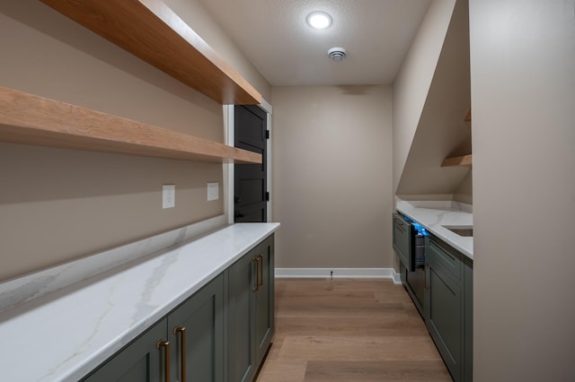 kitchen featuring a textured ceiling, light stone counters, and light wood-type flooring