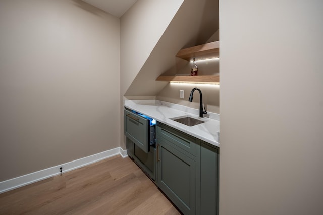 kitchen with light wood-type flooring, light stone counters, and sink