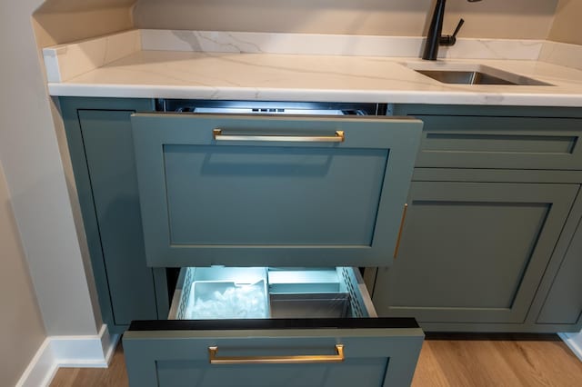 details featuring light wood-type flooring, light stone counters, and sink