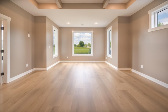 unfurnished room with beam ceiling and light hardwood / wood-style flooring