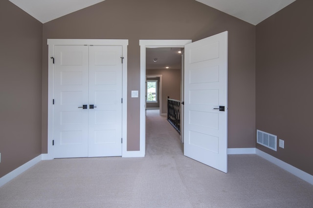 unfurnished bedroom featuring light colored carpet, a closet, and vaulted ceiling