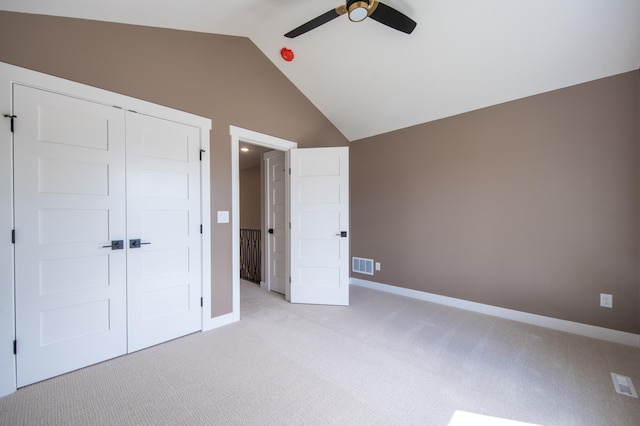 unfurnished bedroom with ceiling fan, light colored carpet, a closet, and vaulted ceiling