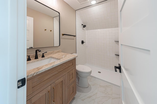 bathroom with toilet, vanity, and tiled shower