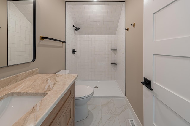 bathroom featuring toilet, vanity, and a tile shower