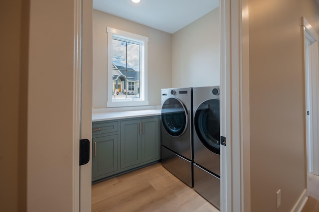 washroom featuring washing machine and dryer, cabinets, and light hardwood / wood-style flooring