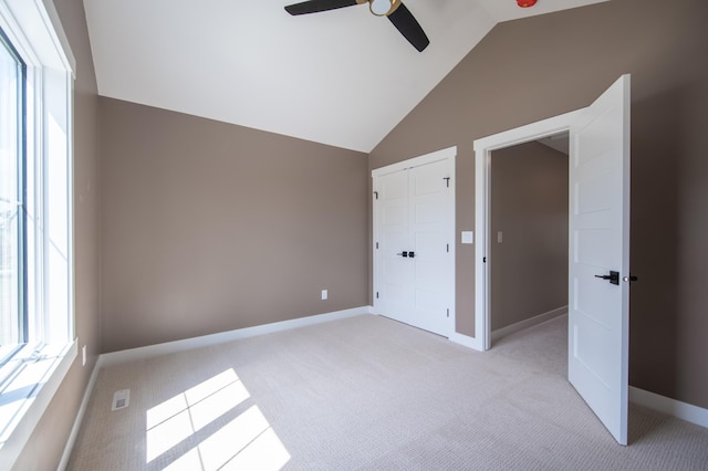 unfurnished bedroom with vaulted ceiling, ceiling fan, a closet, and light colored carpet