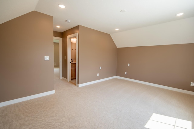 additional living space with light colored carpet and vaulted ceiling