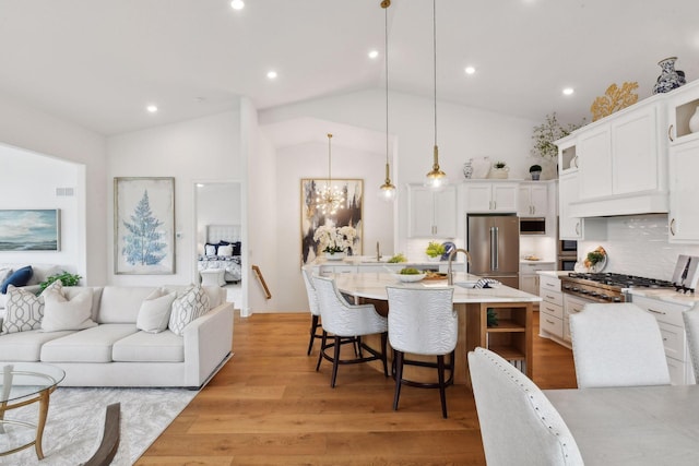 kitchen with white cabinetry, backsplash, lofted ceiling, decorative light fixtures, and a breakfast bar