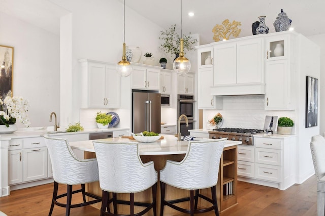 kitchen featuring tasteful backsplash, white cabinets, stainless steel appliances, and decorative light fixtures