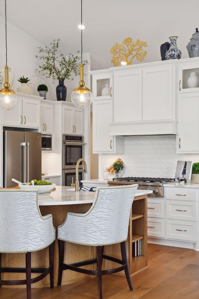 kitchen with backsplash, hanging light fixtures, white cabinets, and stainless steel appliances