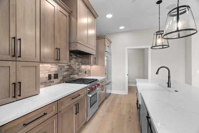 kitchen with high quality appliances, backsplash, sink, light stone countertops, and decorative light fixtures