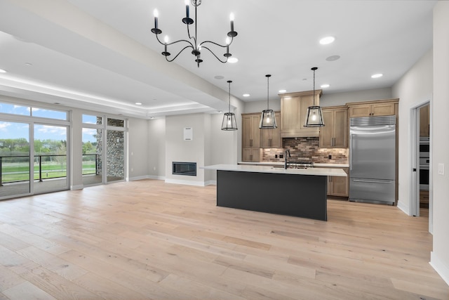 kitchen featuring pendant lighting, sink, decorative backsplash, an island with sink, and appliances with stainless steel finishes