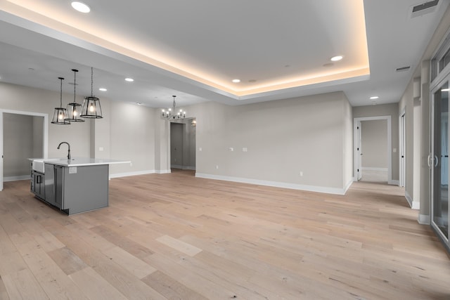 interior space featuring light hardwood / wood-style floors, a raised ceiling, sink, and a chandelier