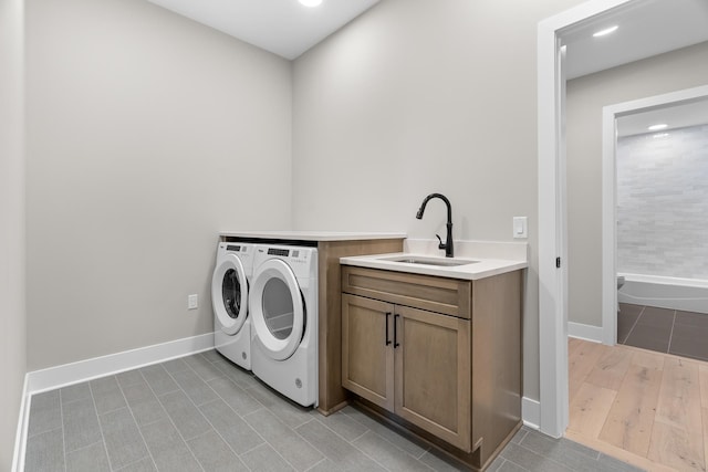 laundry area with cabinets, light tile patterned flooring, washing machine and dryer, and sink