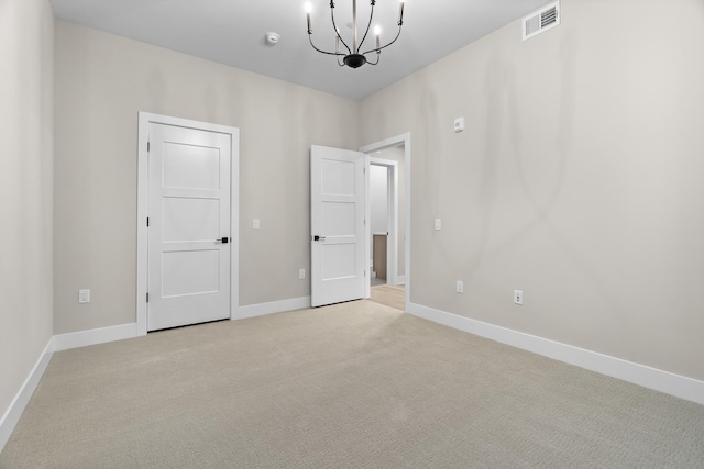 carpeted empty room with a notable chandelier