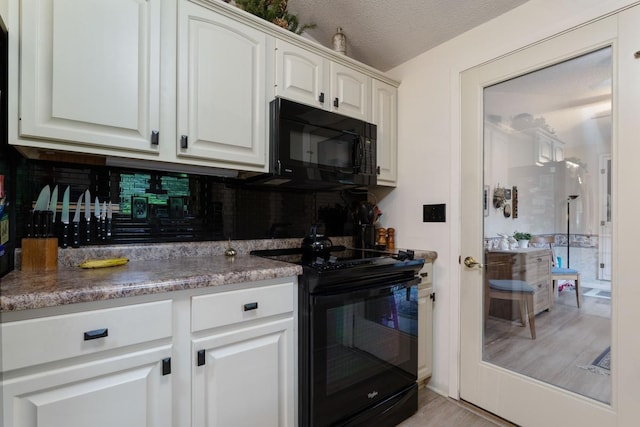 kitchen with white cabinets, backsplash, a textured ceiling, black appliances, and light wood-type flooring