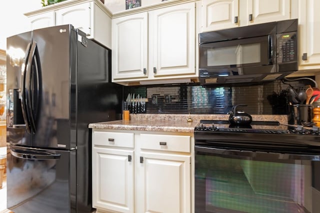 kitchen with light stone countertops, black appliances, white cabinetry, and backsplash