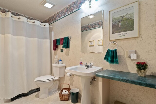 bathroom with a shower with curtain, toilet, and tile patterned floors