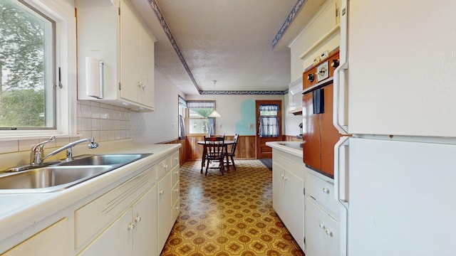 4200 Overlook Dr, Bloomington, MN 55437 - kitchen with freestanding refrigerator, light countertops, a textured ceiling, a wainscoted wall, and white cabinets