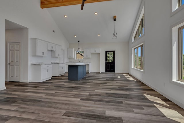 unfurnished living room with sink, high vaulted ceiling, beamed ceiling, and dark hardwood / wood-style floors