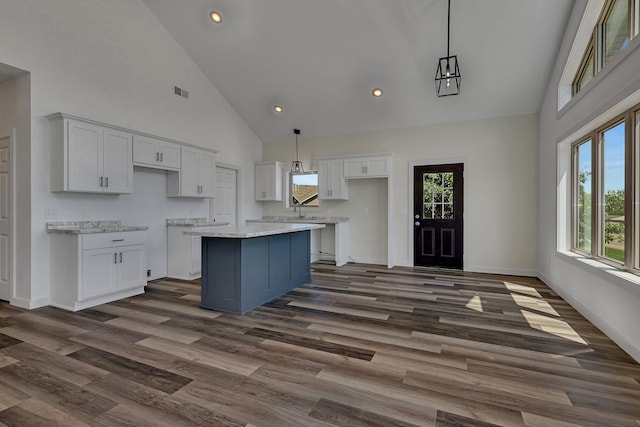 kitchen with high vaulted ceiling, dark hardwood / wood-style flooring, white cabinets, and a kitchen island