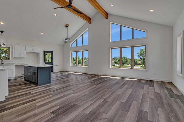 unfurnished living room featuring dark hardwood / wood-style floors, beamed ceiling, sink, and high vaulted ceiling