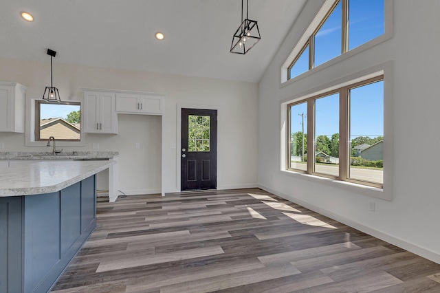 kitchen with decorative light fixtures, high vaulted ceiling, white cabinets, and hardwood / wood-style floors