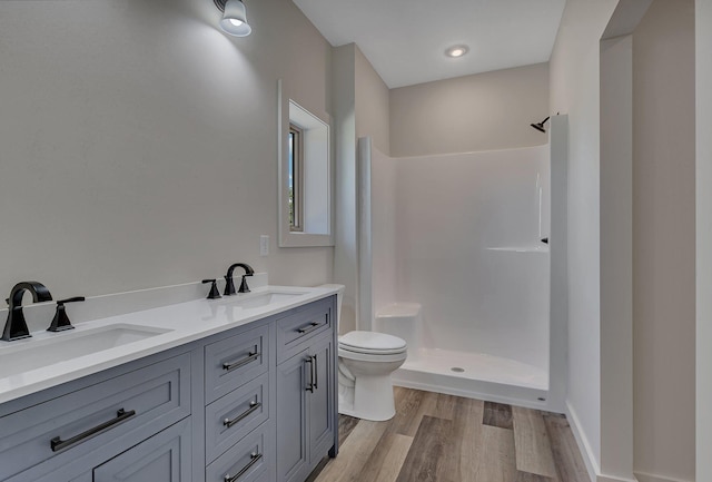 bathroom featuring toilet, hardwood / wood-style floors, walk in shower, and double vanity