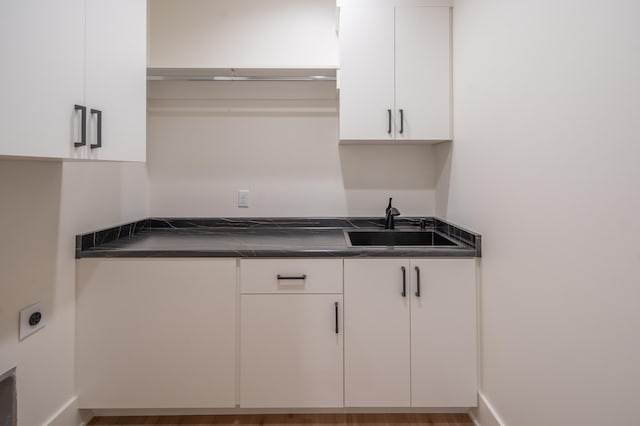 kitchen with white cabinets, dark countertops, and a sink