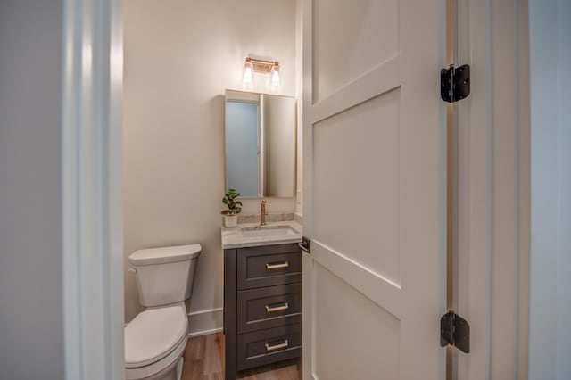 half bathroom featuring toilet, vanity, and wood finished floors