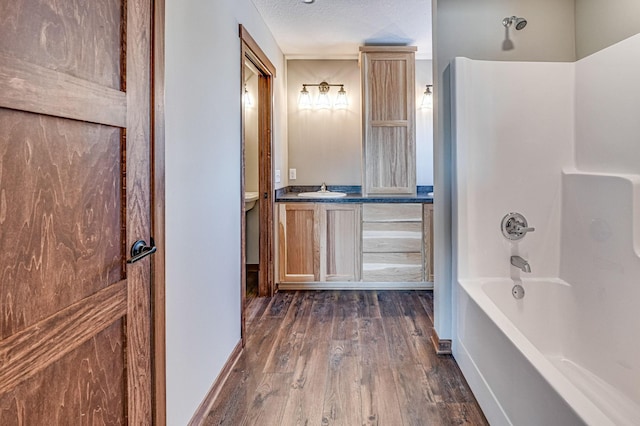 bathroom featuring vanity, wood-type flooring, shower / tub combination, and a textured ceiling