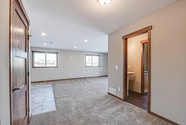 carpeted spare room featuring a textured ceiling