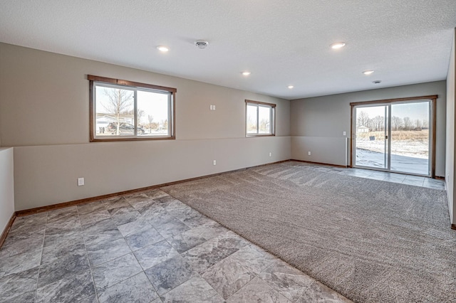 carpeted empty room featuring a textured ceiling