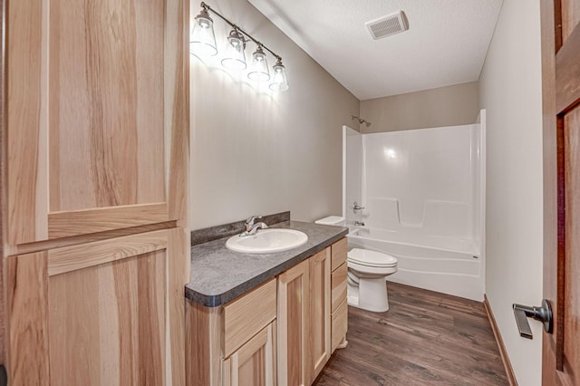 full bathroom featuring hardwood / wood-style flooring, vanity, toilet, bathing tub / shower combination, and a textured ceiling