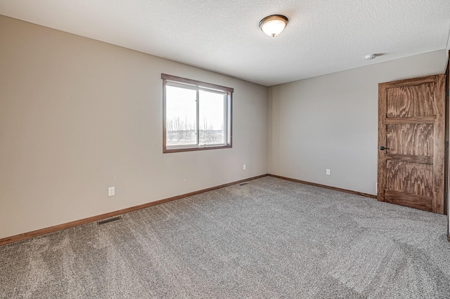 carpeted empty room featuring a textured ceiling