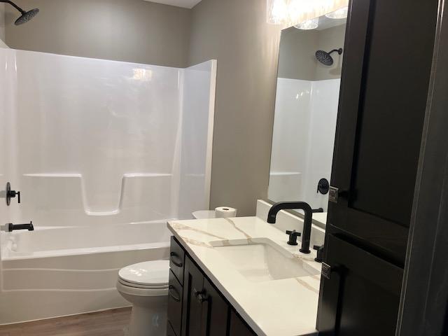 full bathroom with hardwood / wood-style flooring, shower / tub combination, vanity, and toilet