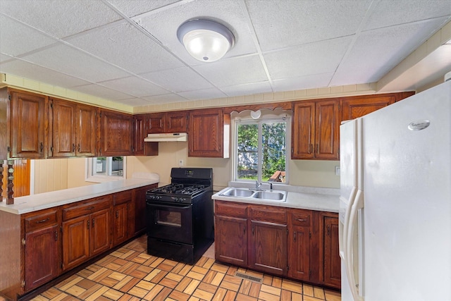 kitchen featuring black gas stove, a drop ceiling, white fridge with ice dispenser, and sink