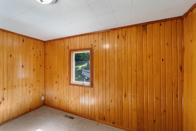 carpeted spare room featuring wood walls